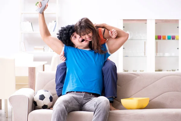 Jovem assistindo futebol com sua esposa em casa — Fotografia de Stock