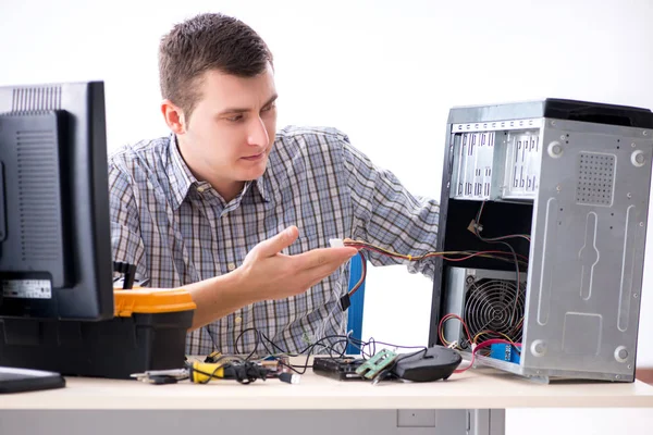 Genç teknisyen atölyede bilgisayar tamir ediyor.