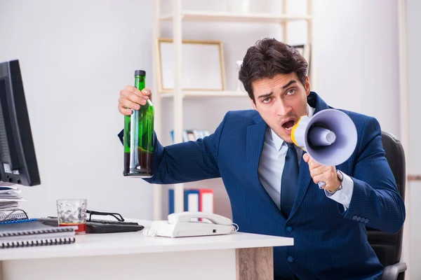 Junger Geschäftsmann trinkt im Büro am Schreibtisch — Stockfoto