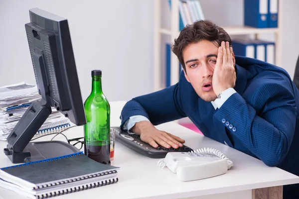 Junger Geschäftsmann trinkt im Büro am Schreibtisch — Stockfoto