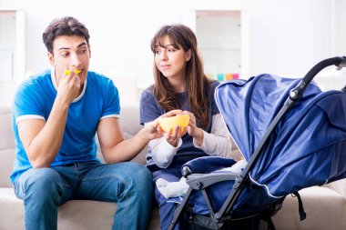 Bebekleri bebek arabasında oturan genç ebeveynler.