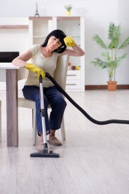 Yaşlı kadın elektrik süpürgesinden yorgun düştü.