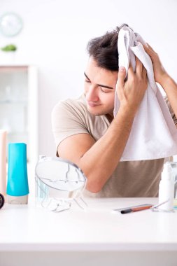 Genç yakışıklı adam aynaya bakıyor. 