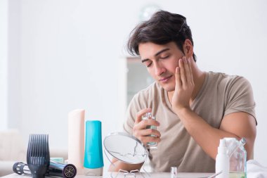 Genç yakışıklı adam aynaya bakıyor. 