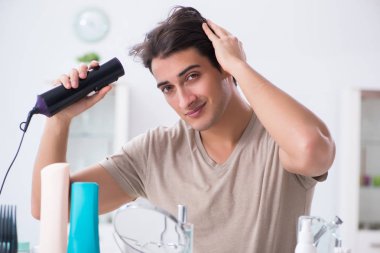 Genç yakışıklı adam aynaya bakıyor. 