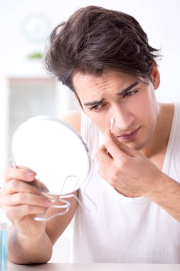 Genç yakışıklı adam aynaya bakıyor. 