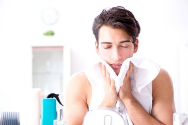 Genç yakışıklı adam aynaya bakıyor. 