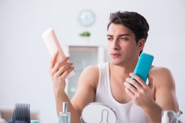 Genç yakışıklı adam aynaya bakıyor. 