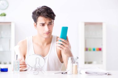 Genç yakışıklı adam aynaya bakıyor. 