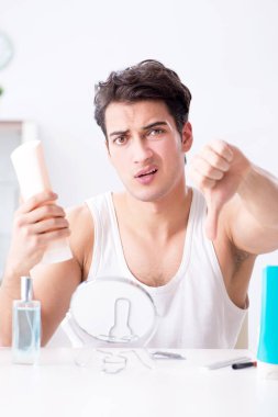 Genç yakışıklı adam aynaya bakıyor. 