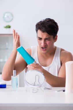 Genç yakışıklı adam aynaya bakıyor. 