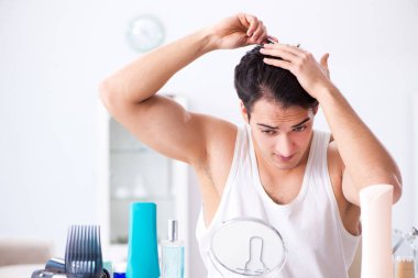 Genç yakışıklı adam aynaya bakıyor. 