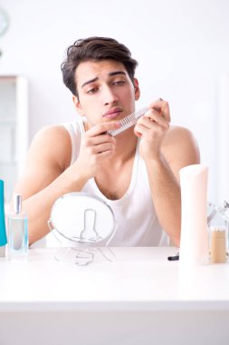 Genç yakışıklı adam aynaya bakıyor. 
