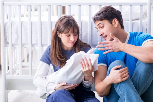 Padres jóvenes con su bebé recién nacido sentado en la alfombra — Foto de Stock