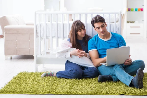 Yeni doğmuş bebekleriyle halıda oturan genç ebeveynler. 