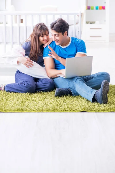 Yeni doğmuş bebekleriyle halıda oturan genç ebeveynler. 