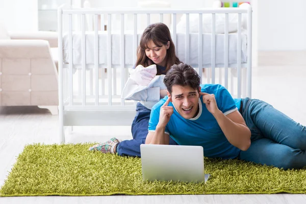 Yeni doğmuş bebekleriyle halıda oturan genç ebeveynler. 