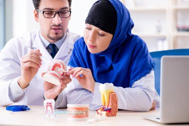 Diş hekimi ve asistanı yeni diş implantı üzerinde çalışıyor.