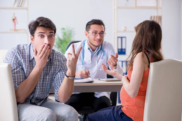 Pregnant woman with her husband visiting the doctor in clinic — Stock Photo, Image