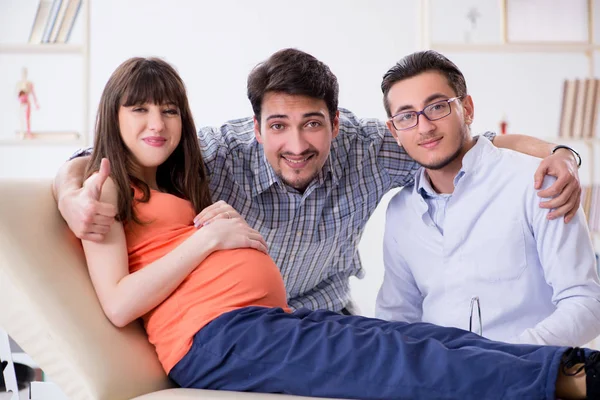 Hamile kadın kocasıyla klinikteki doktoru ziyaret ediyor.