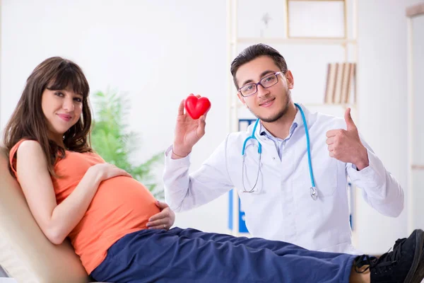Беременная женщина с мужем, посещающая врача в клинике — стоковое фото