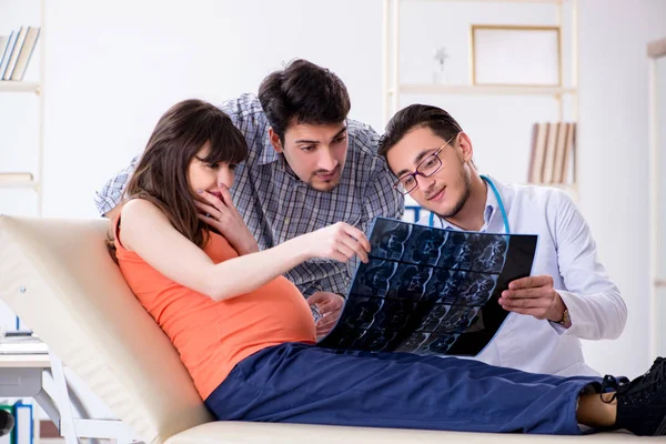 Hamile kadın kocasıyla klinikteki doktoru ziyaret ediyor.