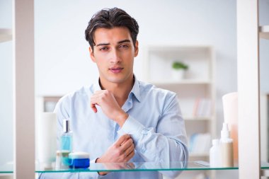 Adam banyoda çalışmak için giyiniyor.