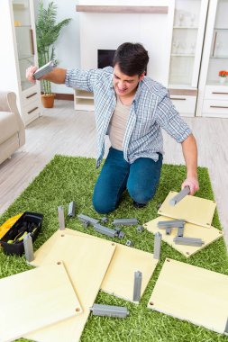 Adam evde mobilya montajı yapıyor.