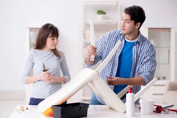 Ehefrau hilft Ehemann, kaputten Stuhl zu Hause zu reparieren — Stockfoto