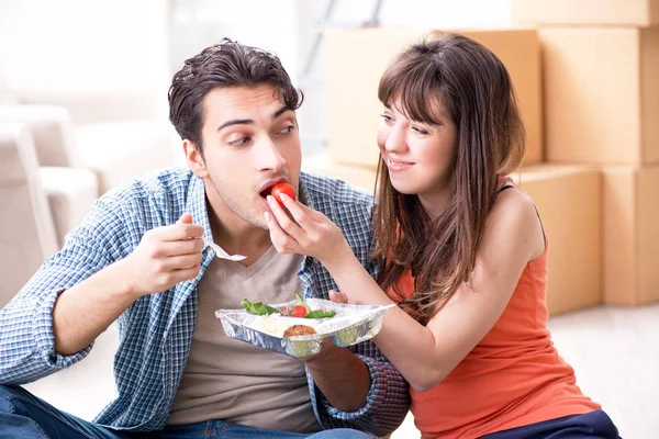 Mladá rodina jíst jídlo v novém bytě po přestěhování v — Stock fotografie