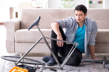 Evde bisiklet tamir eden genç bir adam.