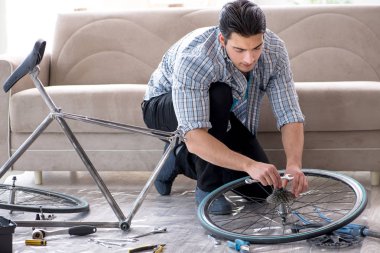 Evde bisiklet tamir eden genç bir adam.