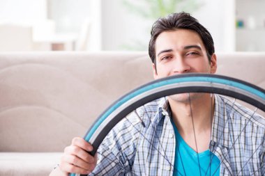 Evde bisiklet tamir eden genç bir adam.