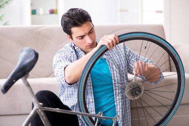 Evde bisiklet tamir eden genç bir adam.