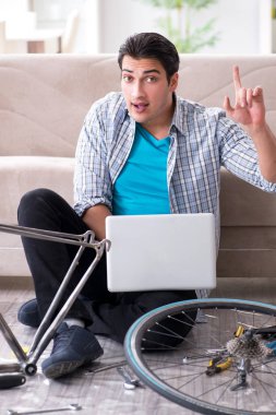 Evde bisiklet tamir eden genç bir adam.