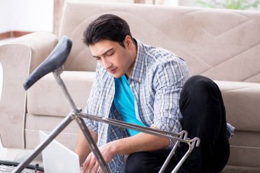 Evde bisiklet tamir eden genç bir adam.