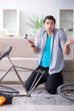 Evde bisiklet tamir eden genç bir adam.