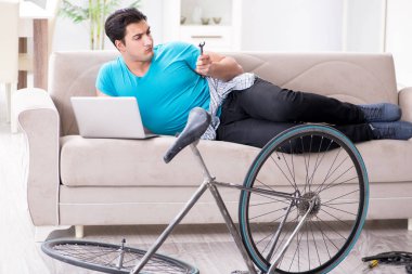 Evde bisiklet tamir eden genç bir adam.