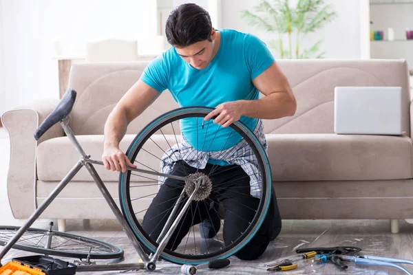 Evde bisiklet tamir eden genç bir adam.