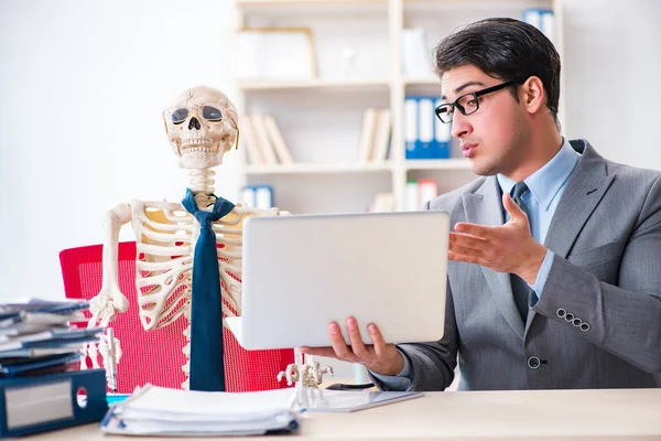 Businessman working with skeleton in office — Stock Photo, Image