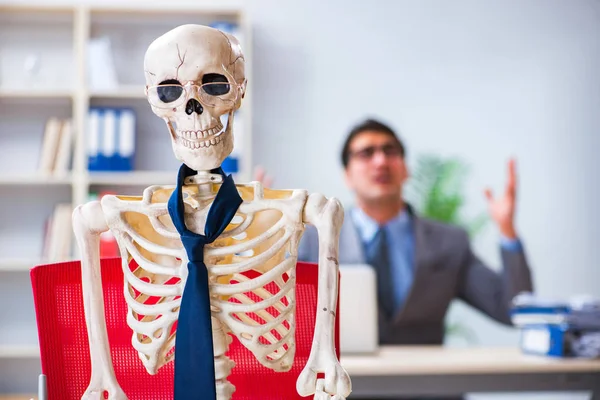 Empresario trabajando con el esqueleto en la oficina — Foto de Stock