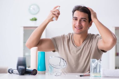 Genç yakışıklı adam aynaya bakıyor. 