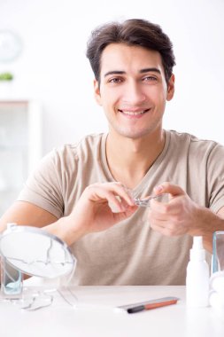 Genç yakışıklı adam aynaya bakıyor. 