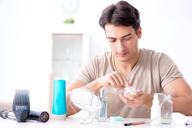 Genç yakışıklı adam aynaya bakıyor. 