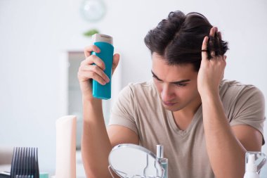 Genç yakışıklı adam aynaya bakıyor. 