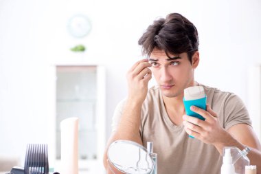 Genç yakışıklı adam aynaya bakıyor. 