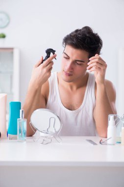 Genç yakışıklı adam aynaya bakıyor. 