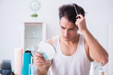 Genç yakışıklı adam aynaya bakıyor. 