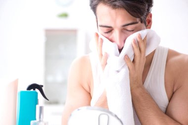 Genç yakışıklı adam aynaya bakıyor. 