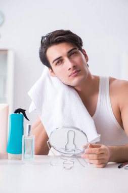 Genç yakışıklı adam aynaya bakıyor. 